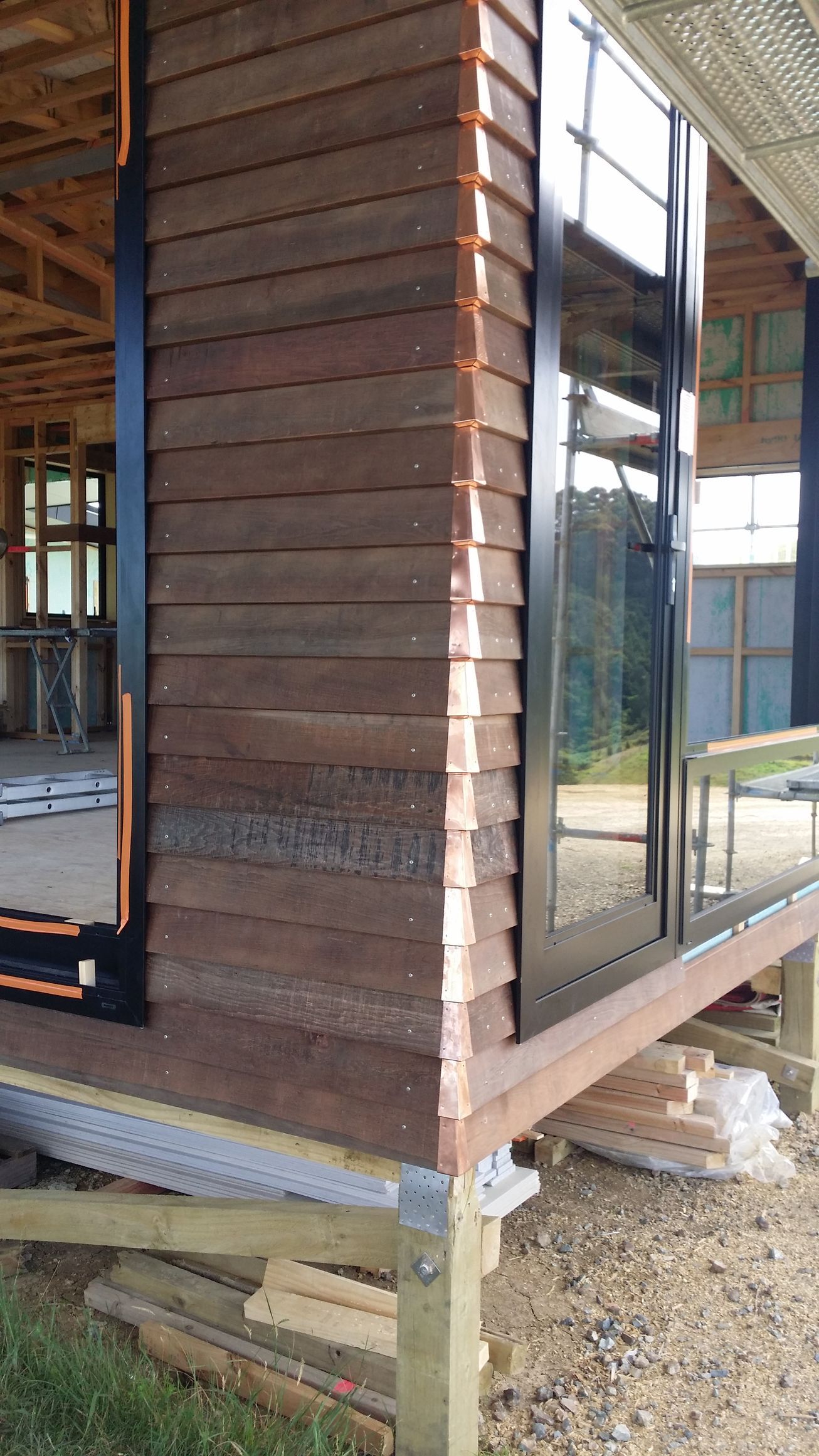 A house is being built with wooden siding and copper trim.