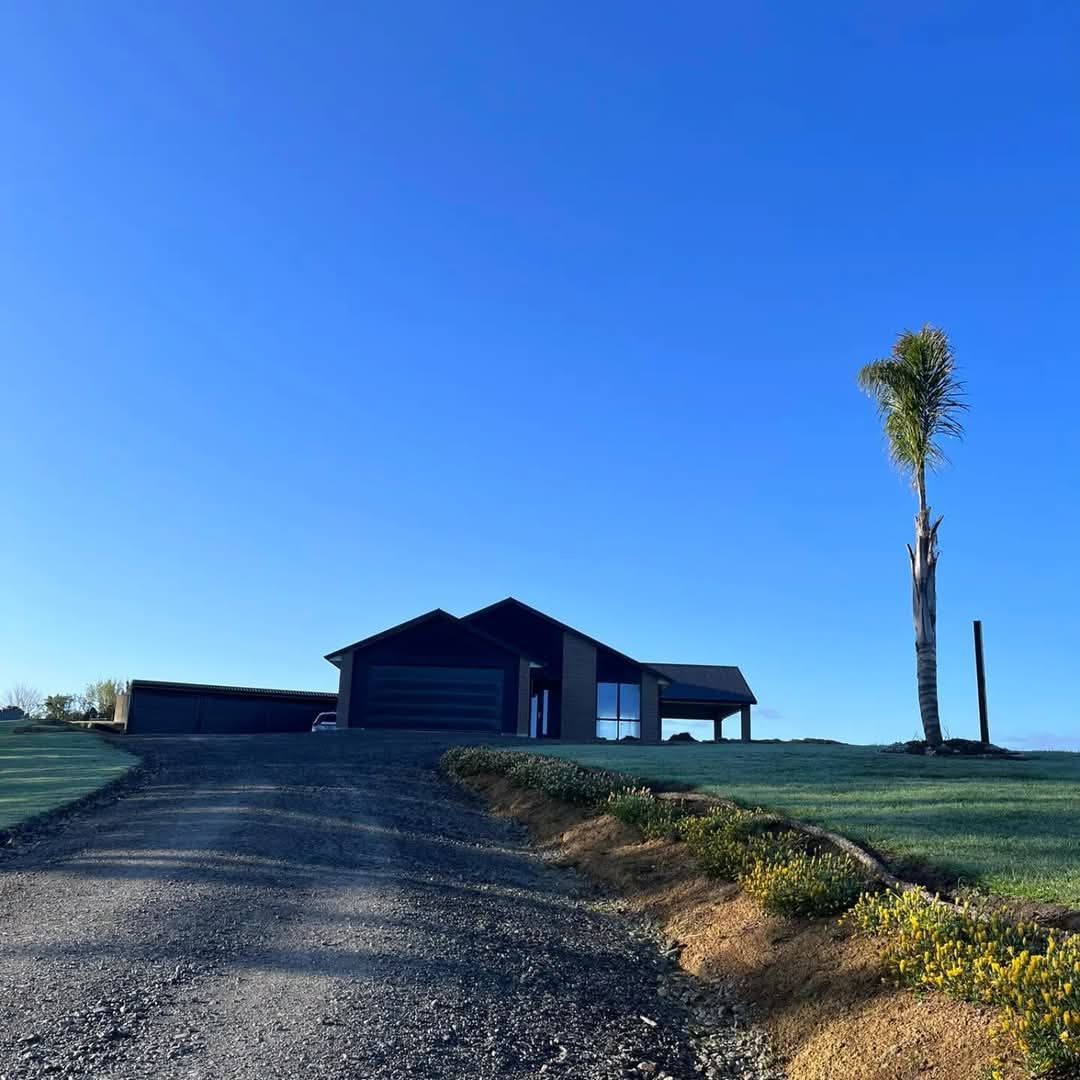 A dirt road leading to a house with a tree in the foreground