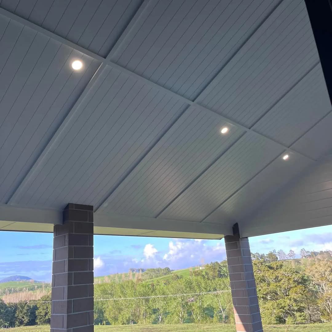 The ceiling of a porch with a view of a field and trees.