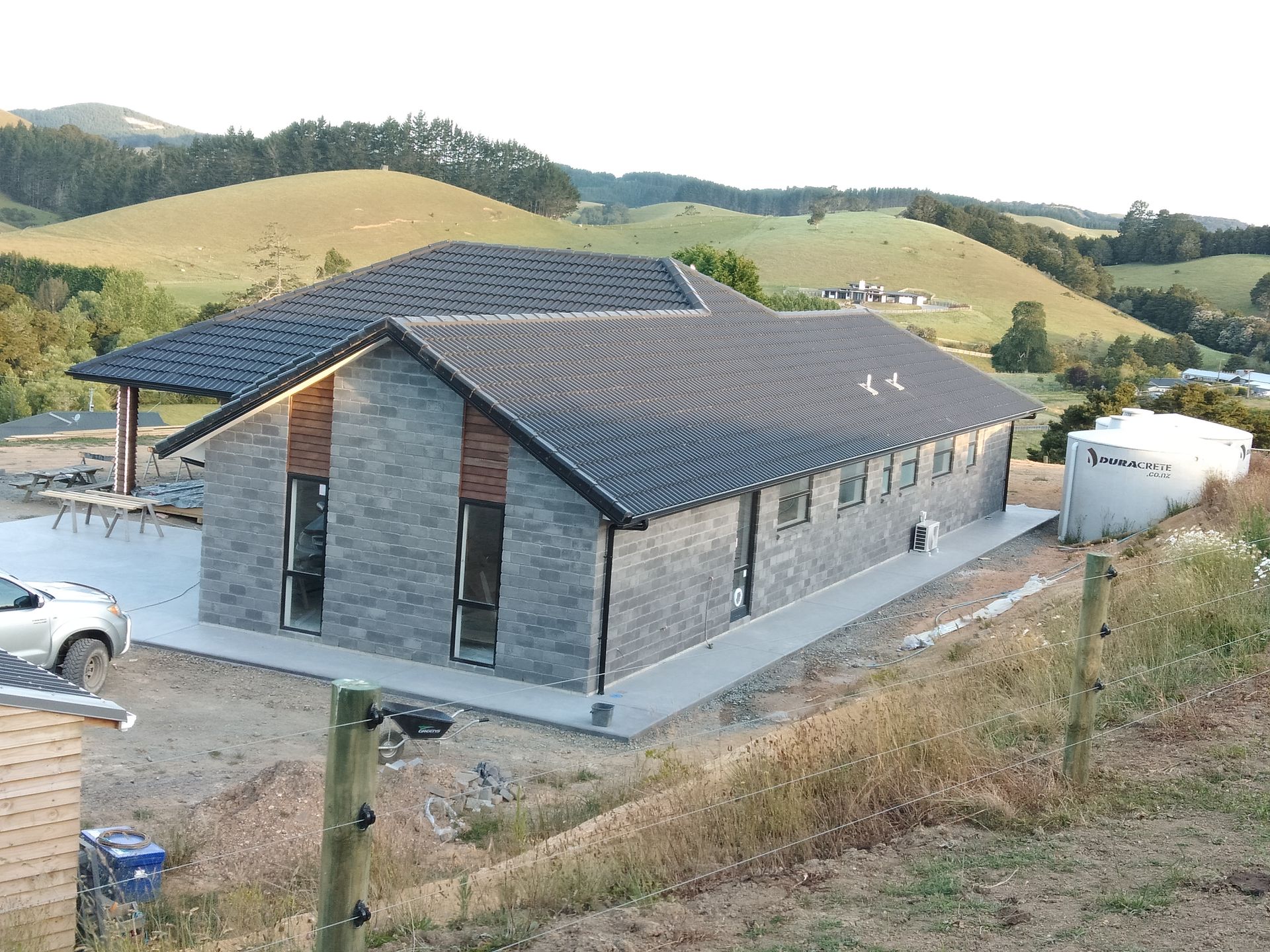A house is sitting on top of a hill with a car parked in front of it.
