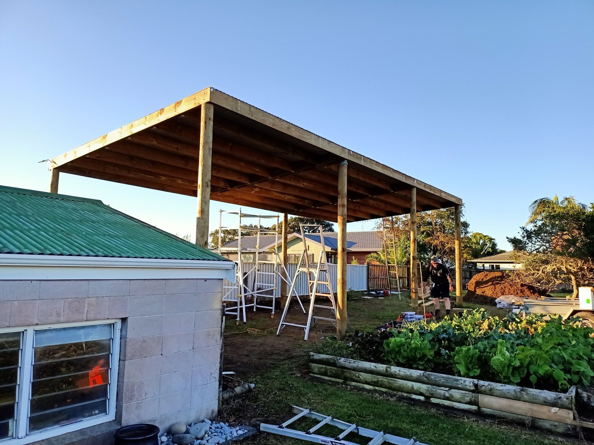 A wooden structure is being built in the backyard of a house.