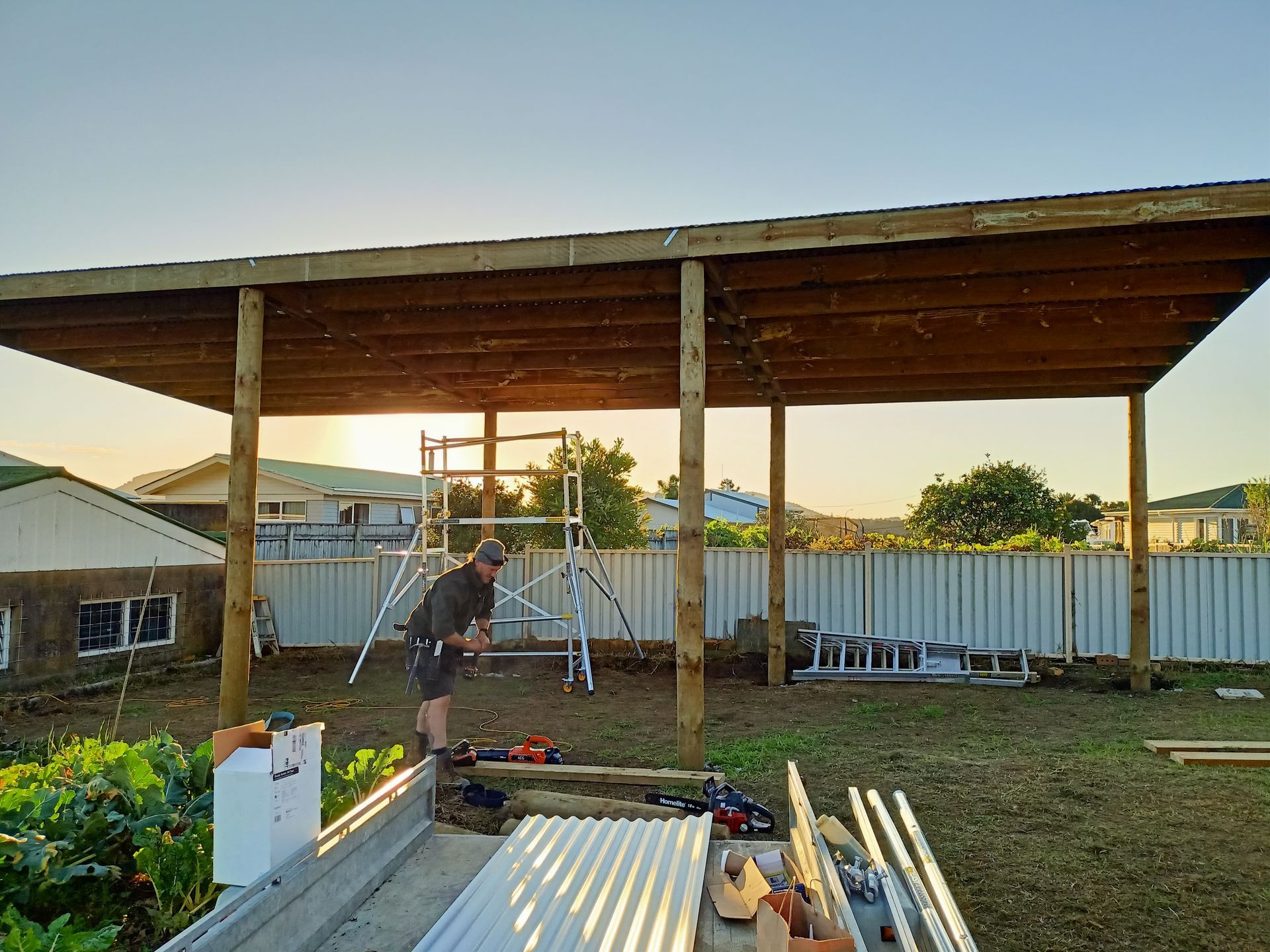 A man is working on a wooden structure in a backyard.