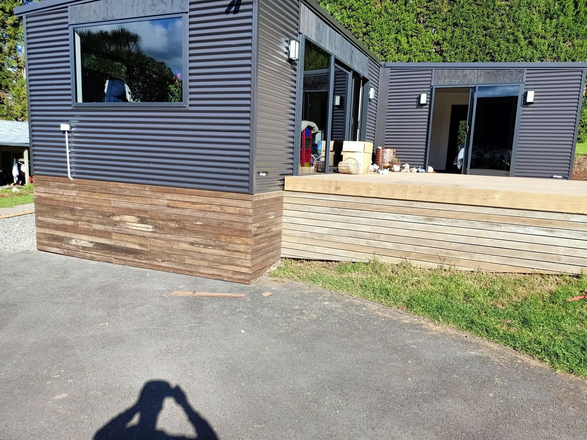 A shadow of a person is cast on the ground in front of a house.