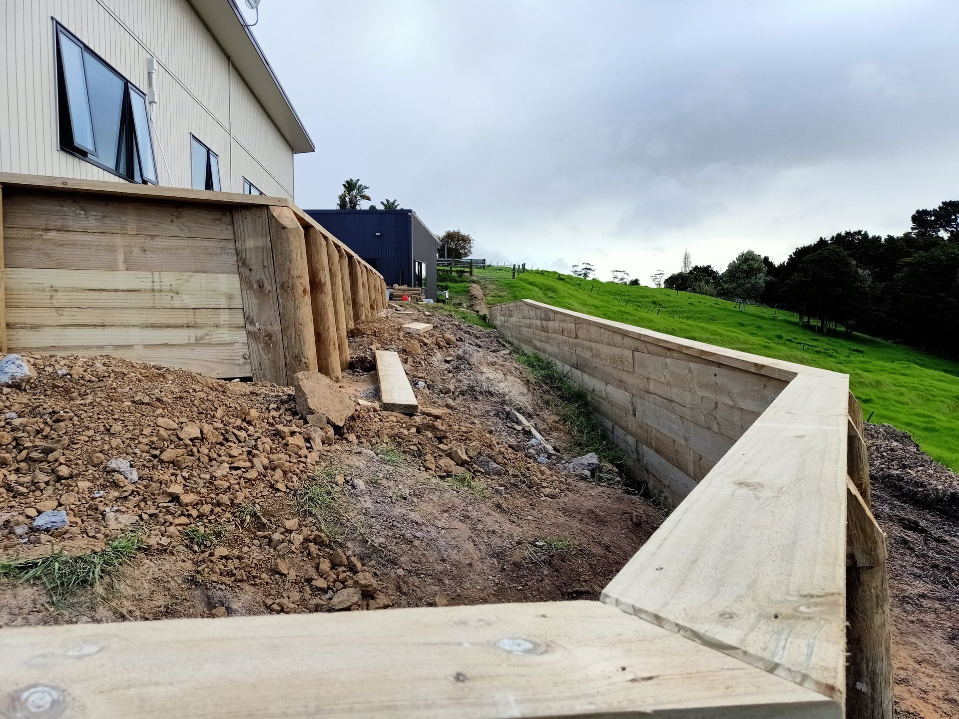 A wooden fence is being built on a hill next to a house.