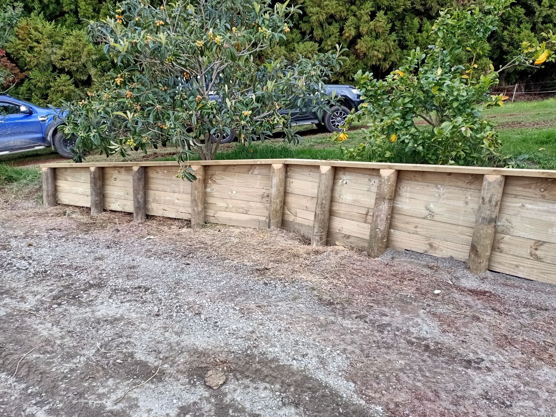 A blue car is parked next to a wooden wall.