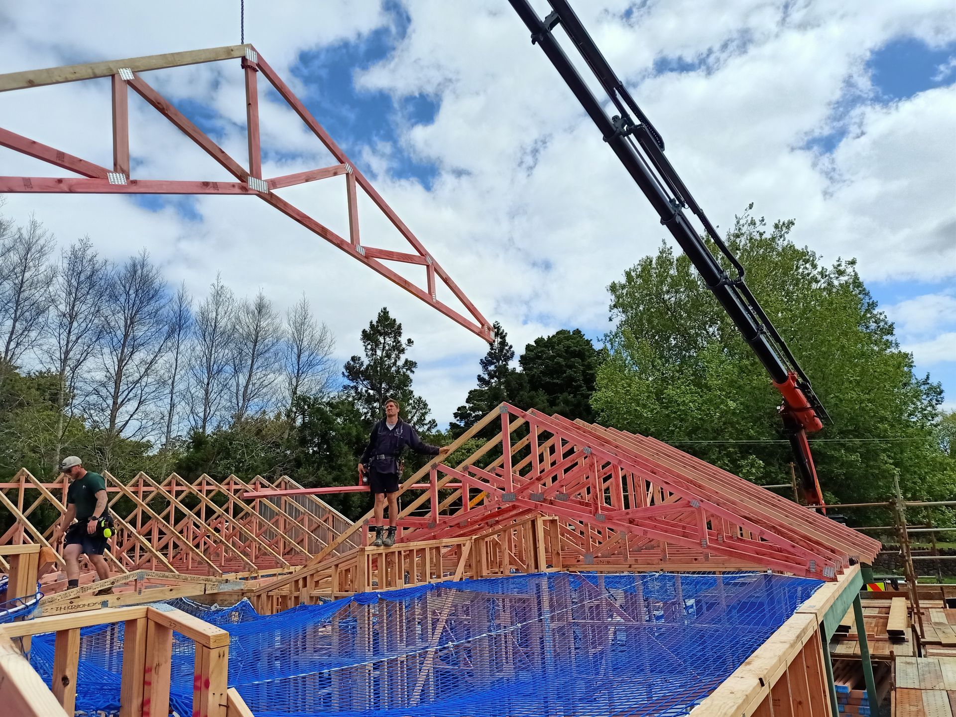 A crane is lifting a wooden structure on top of a building under construction.
