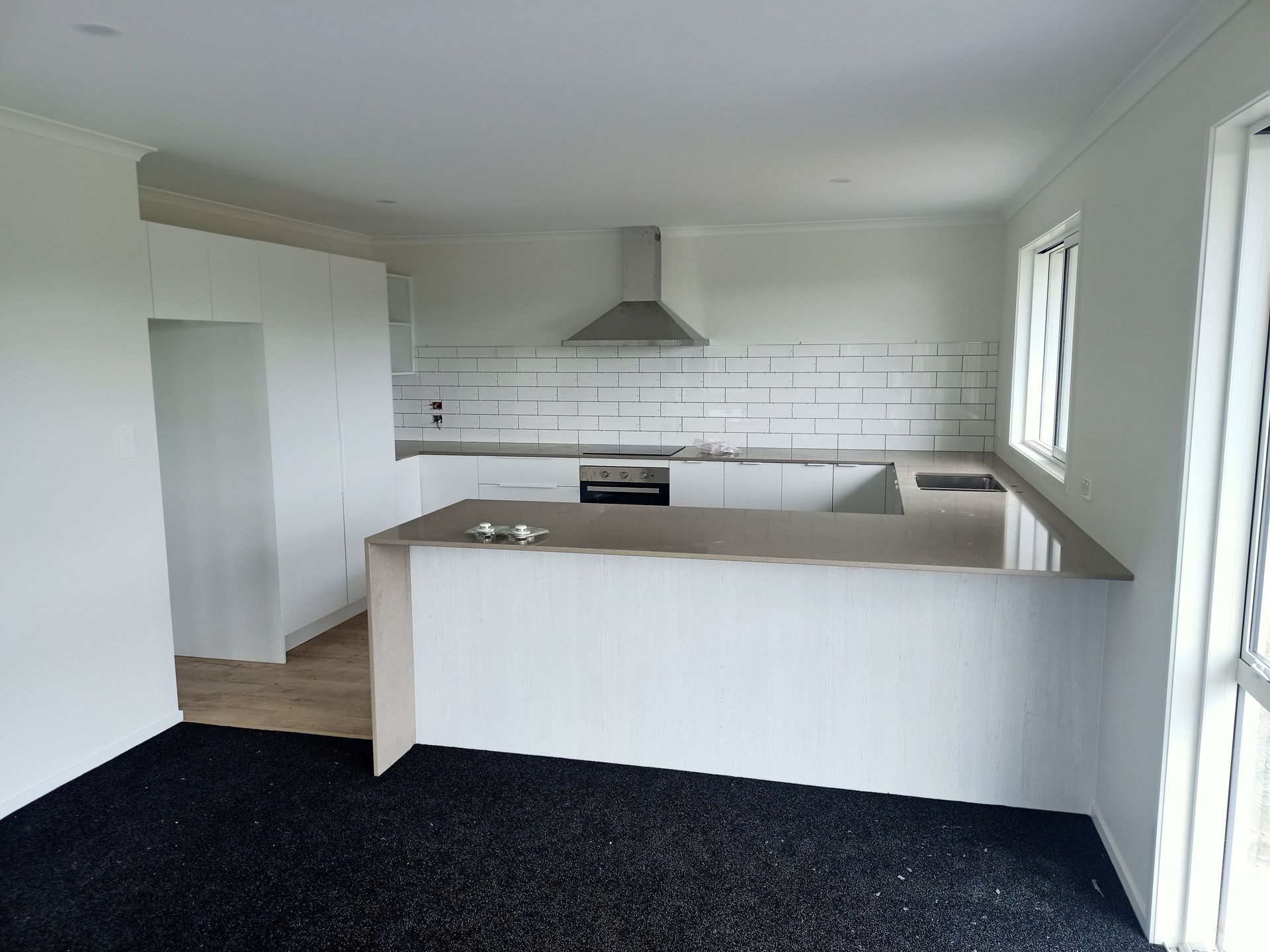 An empty kitchen with white cabinets and black carpet