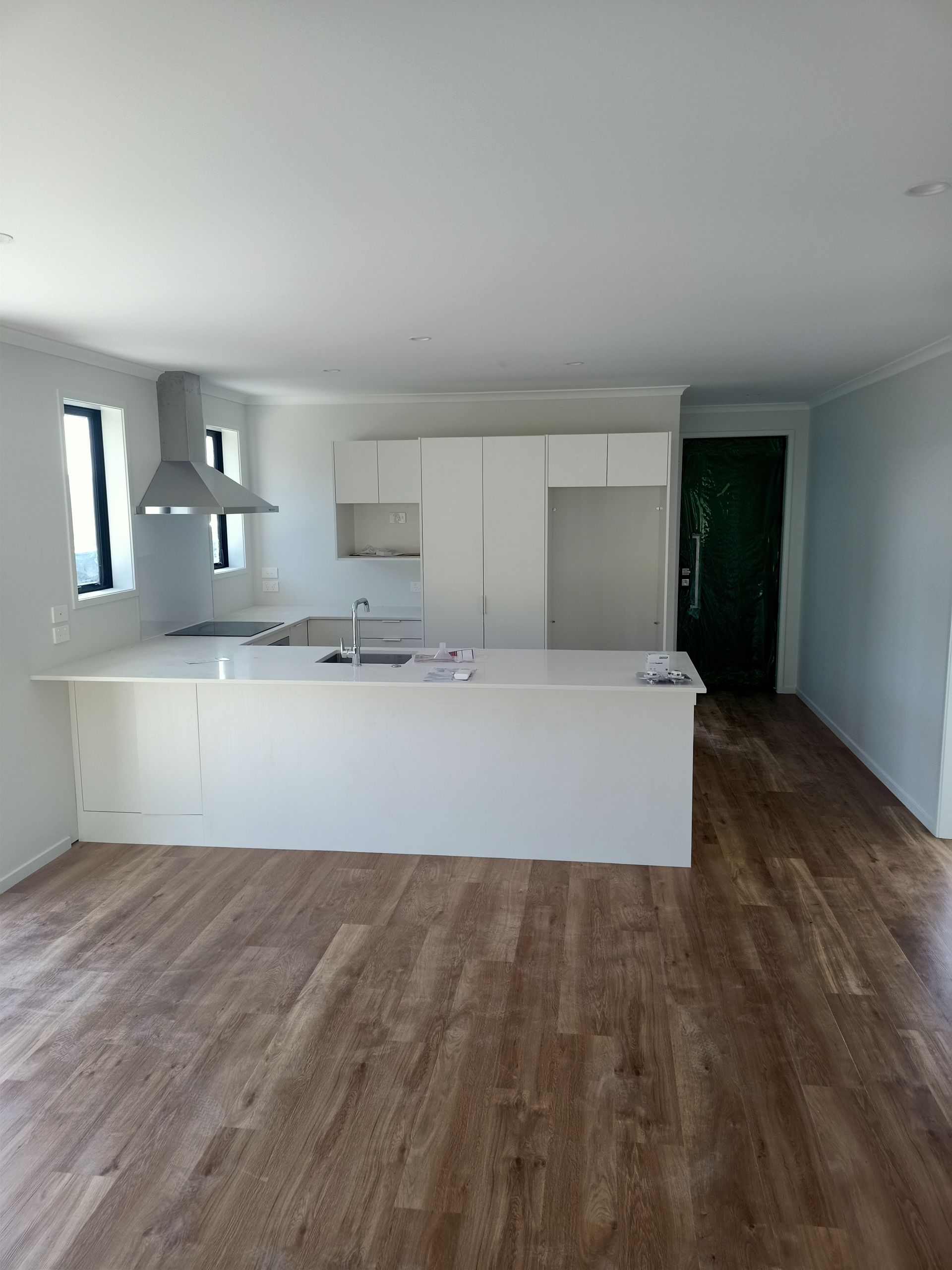 An empty kitchen with white cabinets and wooden floors.