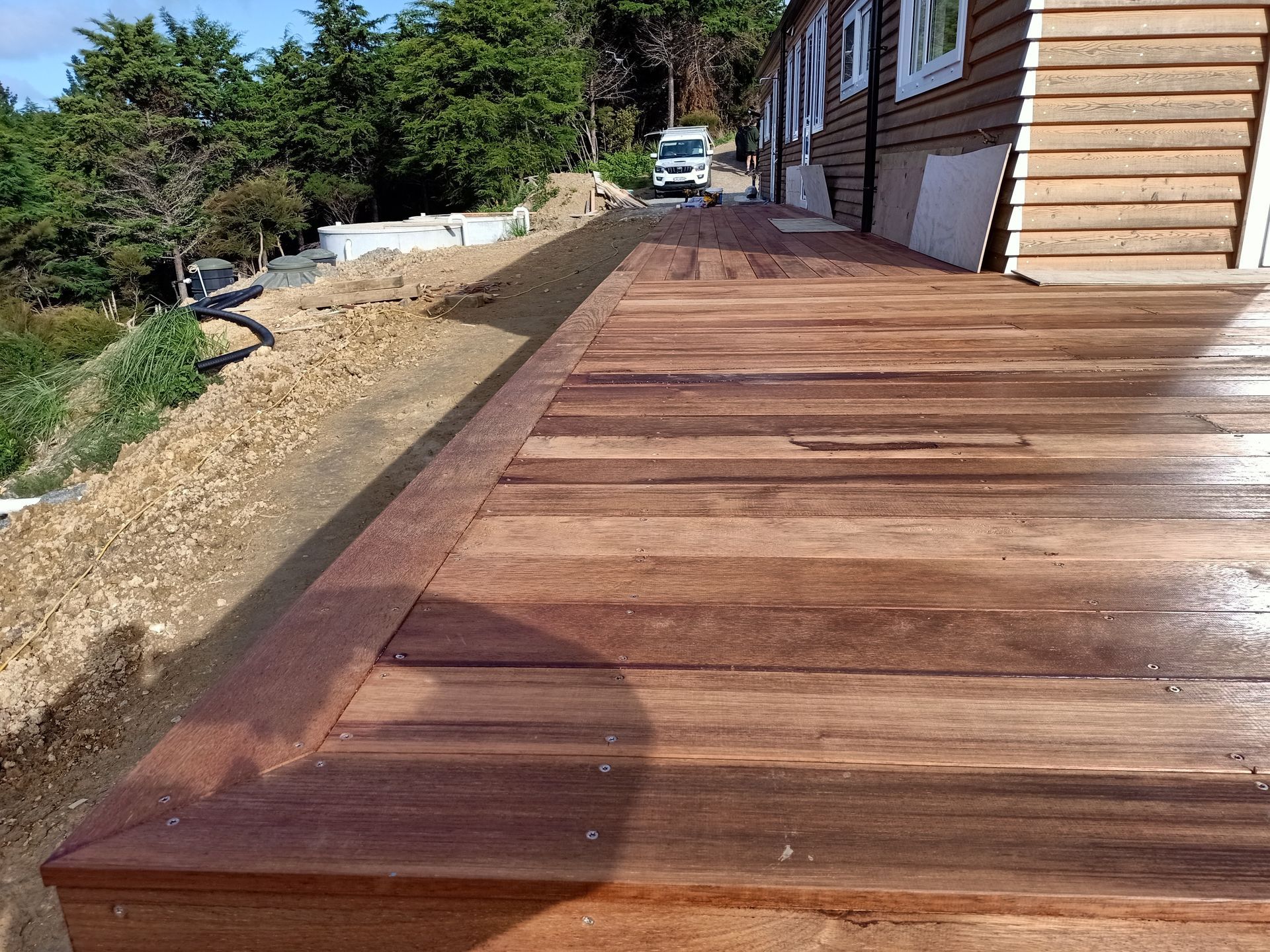 A wooden deck is sitting on top of a hill next to a house.