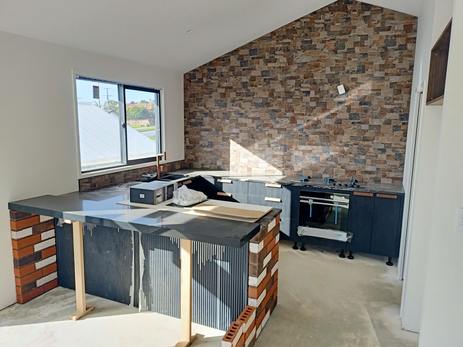 A kitchen under construction with a brick wall and a large island.