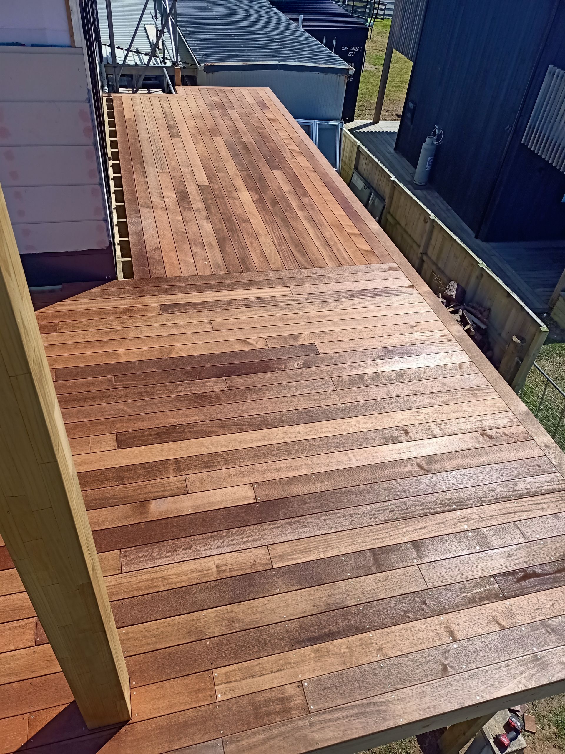 A wooden deck with stairs leading up to it and a building in the background.