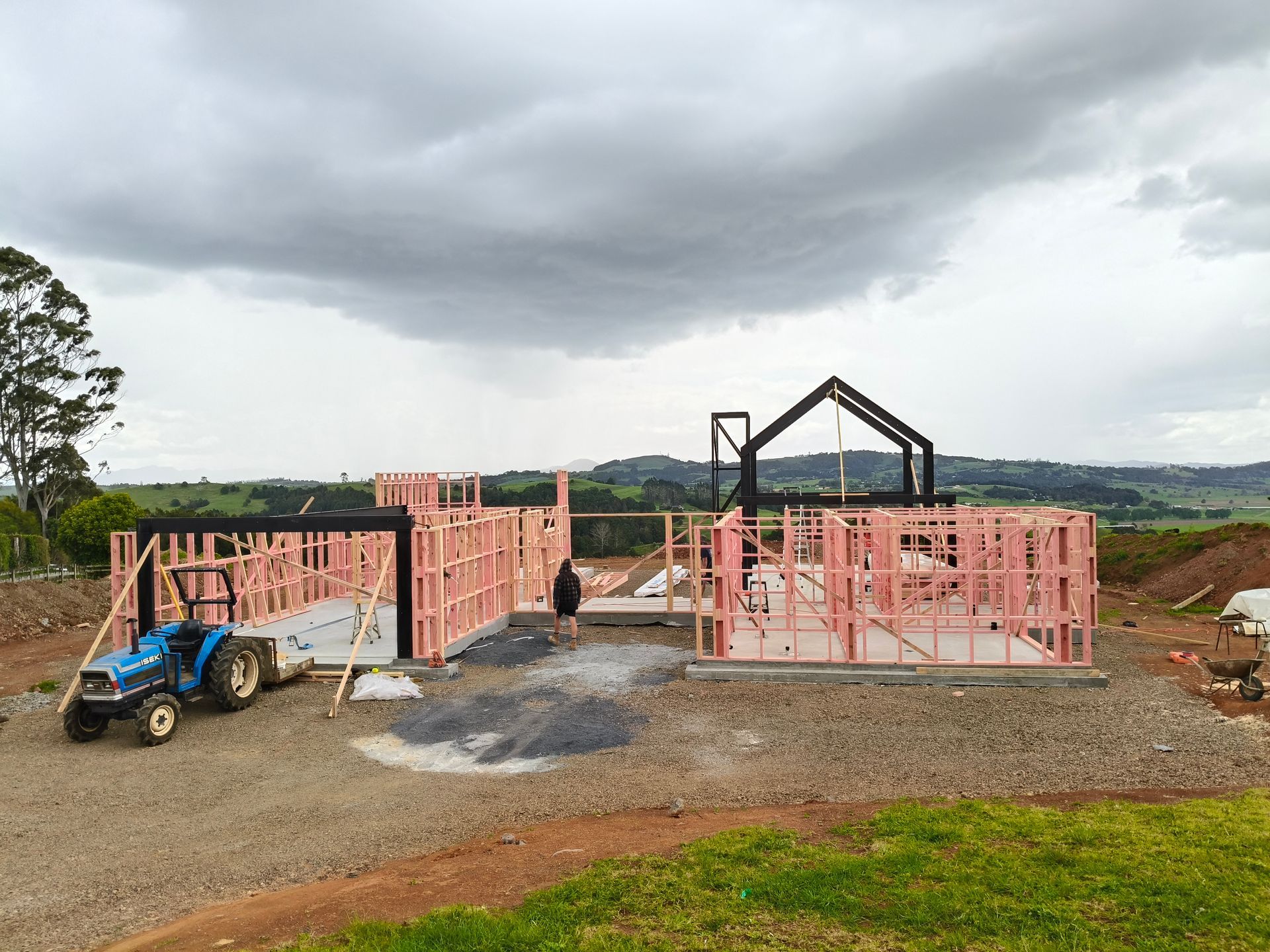 A tractor is parked in front of a house under construction.