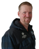 A man with a beard wearing a jacket that says ' precision construction ' on it