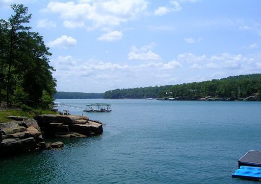 A wooden chair sits on a dock overlooking a body of water