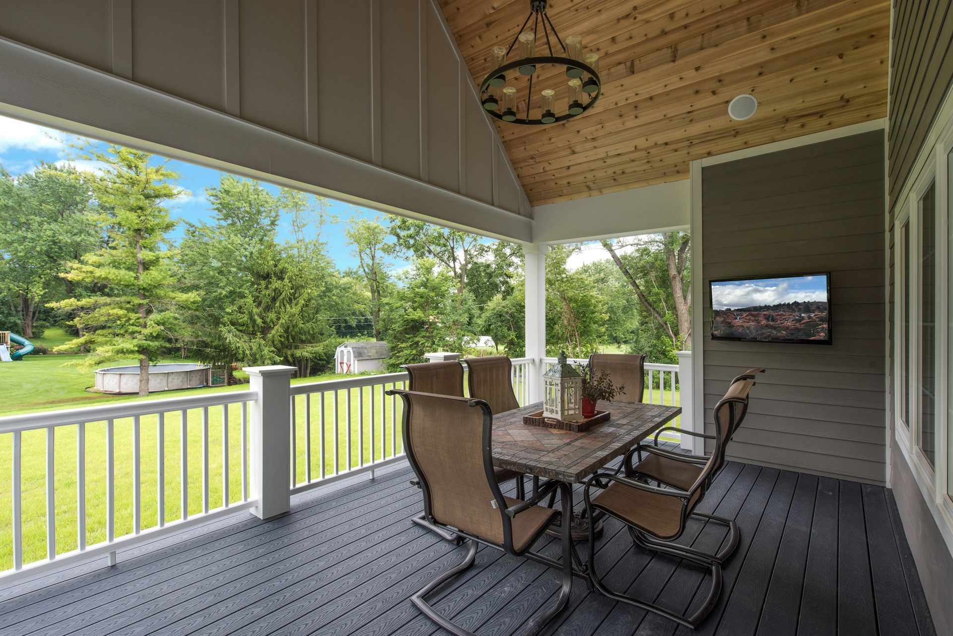 A porch with a table and chairs and a television on the wall.