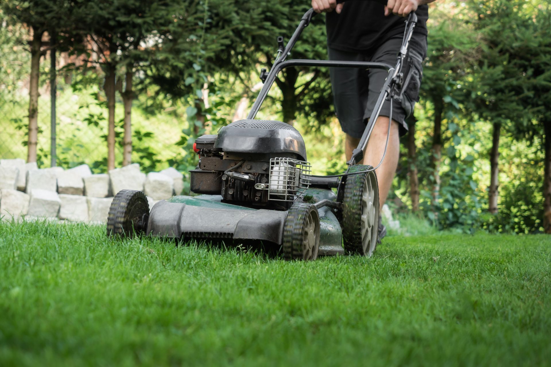 A man is mowing his lawn with a lawn mower.