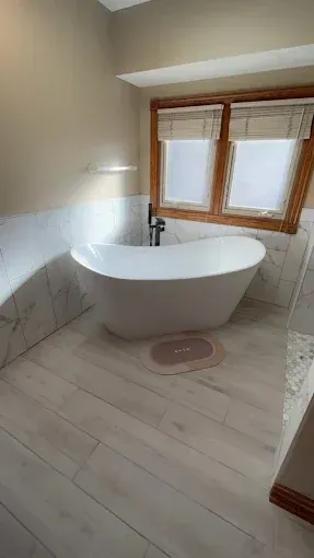 A bathroom with a bathtub and two windows.