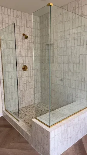 A walk in shower with a glass door in a bathroom.