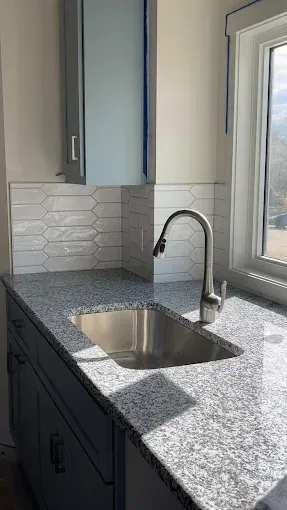 A kitchen with granite counter tops and a stainless steel sink.