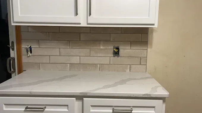 A kitchen with white cabinets and a white counter top.