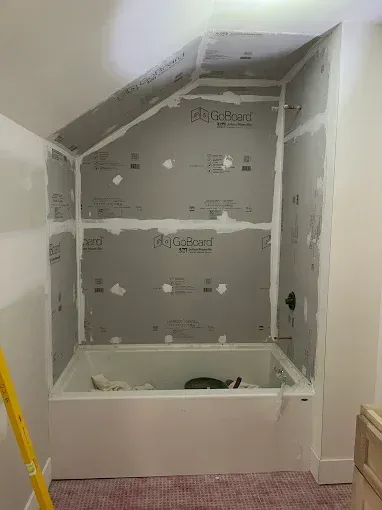 A bathtub is sitting in a bathroom under a slanted ceiling.