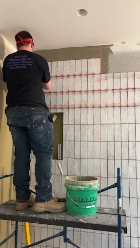 A man is standing on a scaffolding painting a wall.