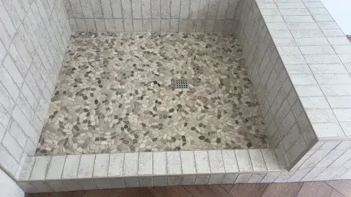 A shower stall with a tiled floor and a drain.