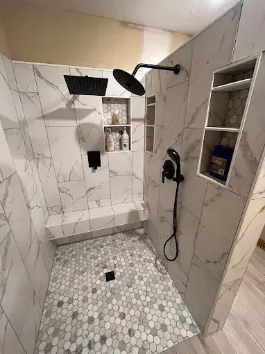 A bathroom with a walk in shower and a black shower head.
