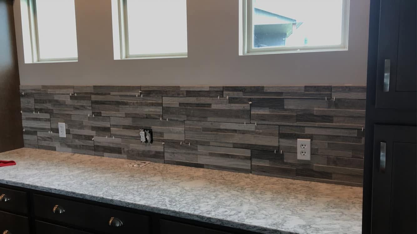A kitchen with granite counter tops and a stone backsplash.