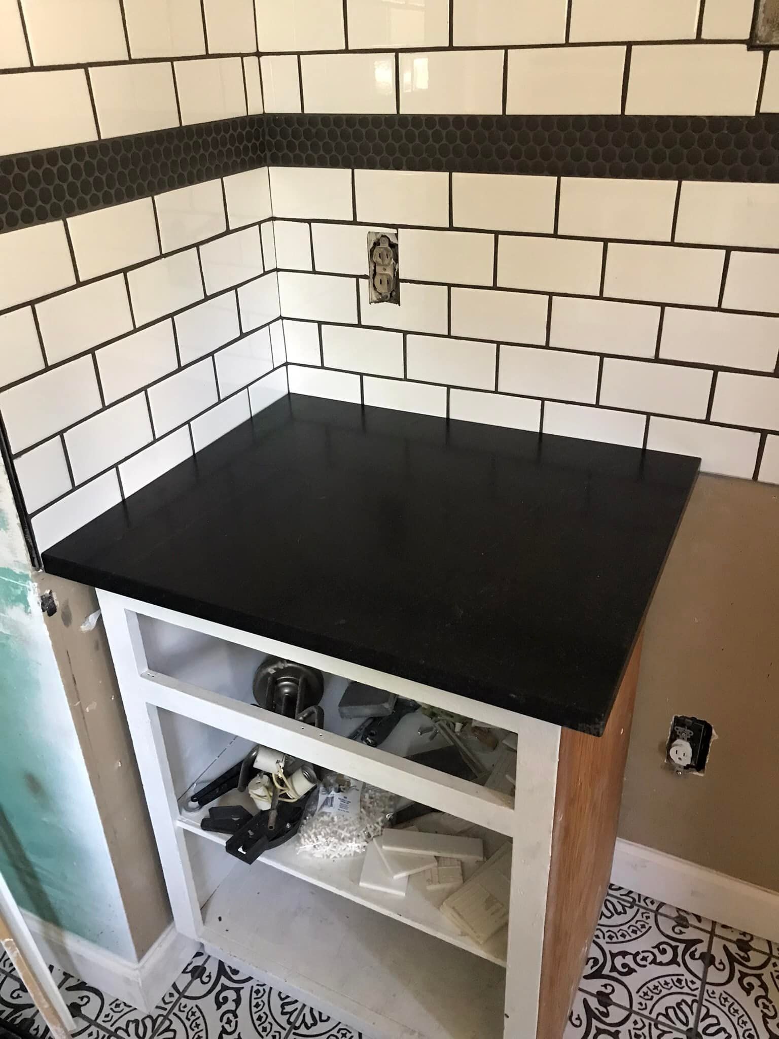 A black counter top is sitting on top of a white cabinet.