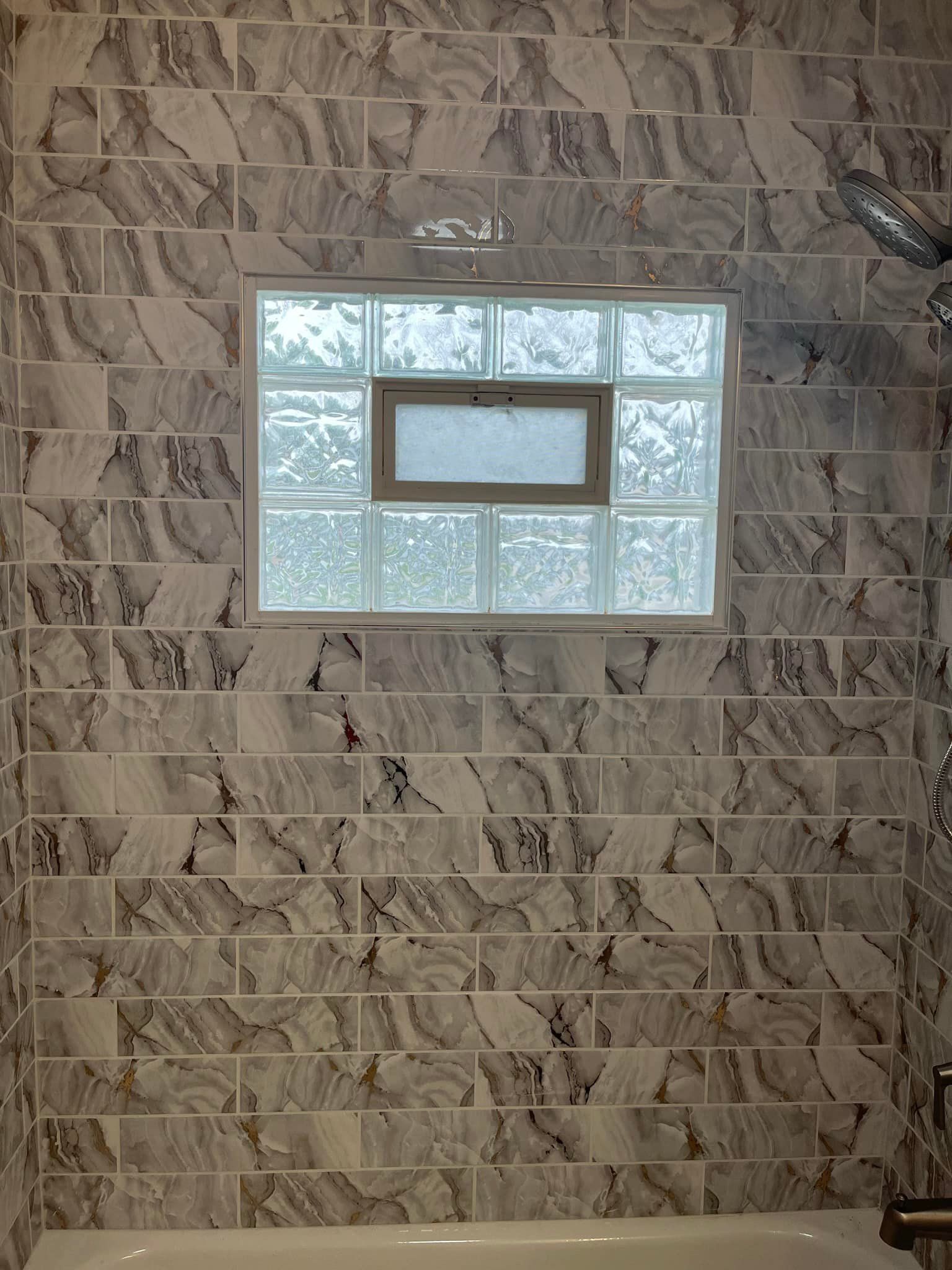 A bathroom with marble tiles and a glass block window.