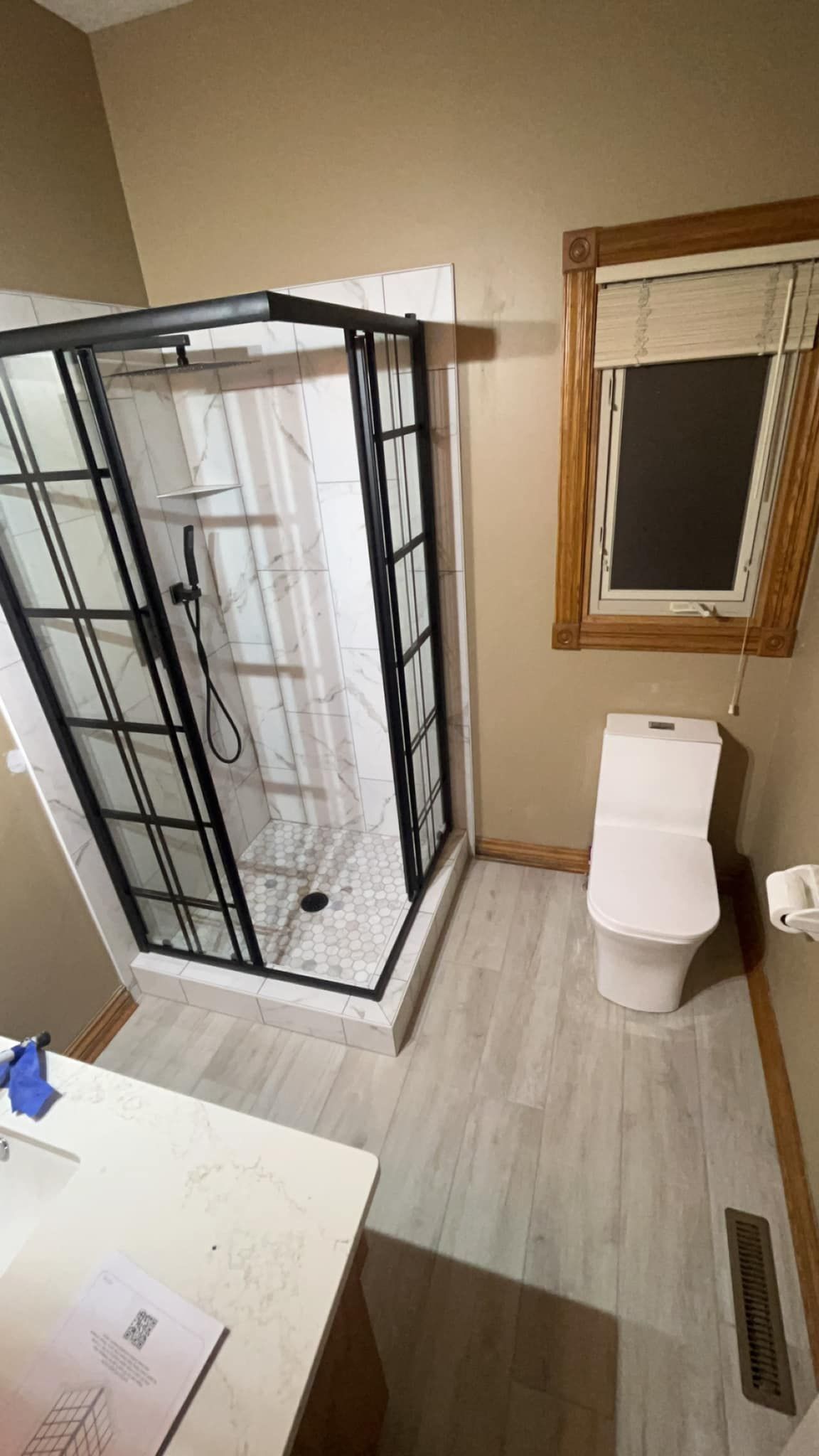 A bathroom with a toilet , shower and window.