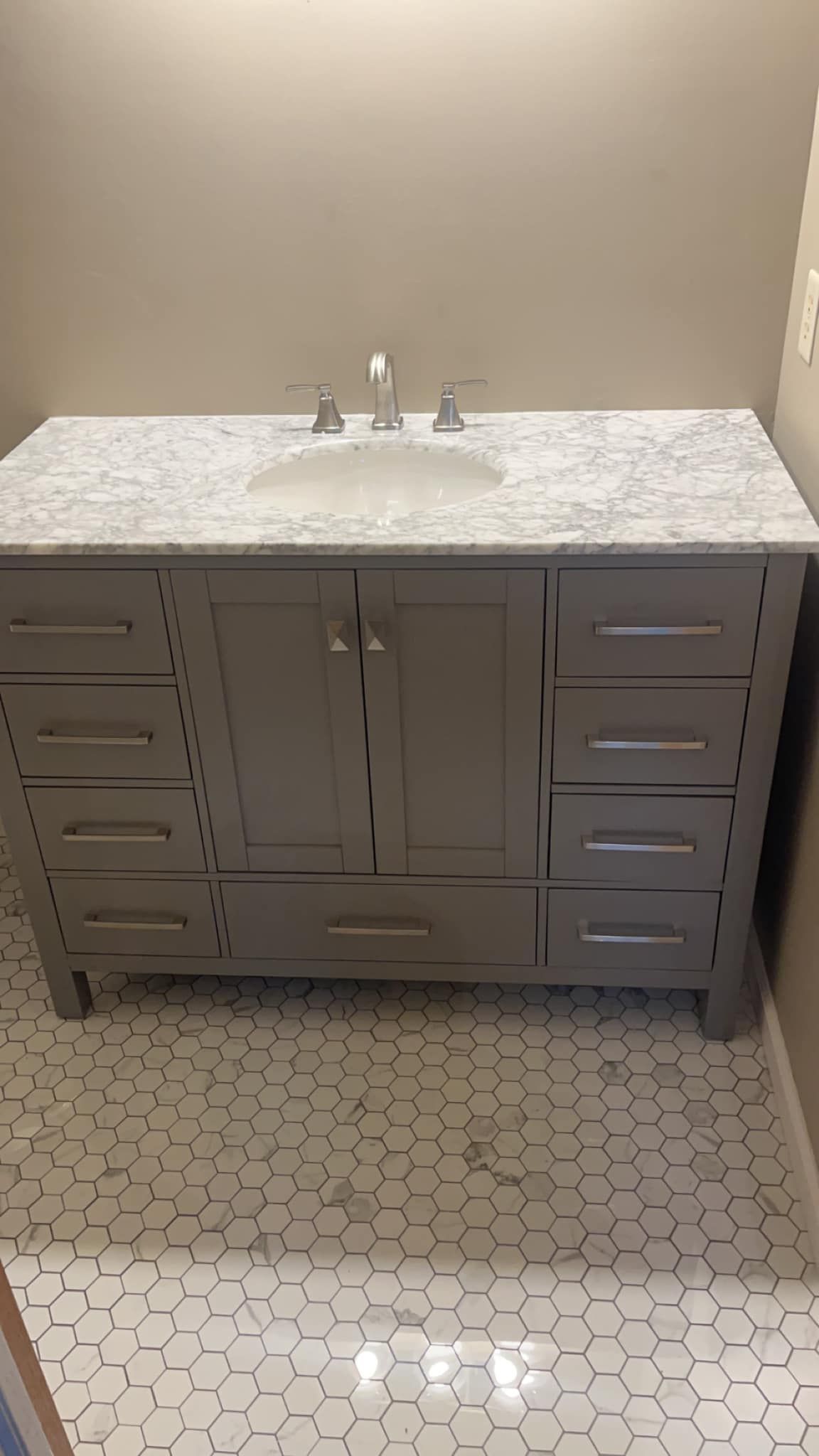 A bathroom vanity with a sink , drawers and a marble counter top.