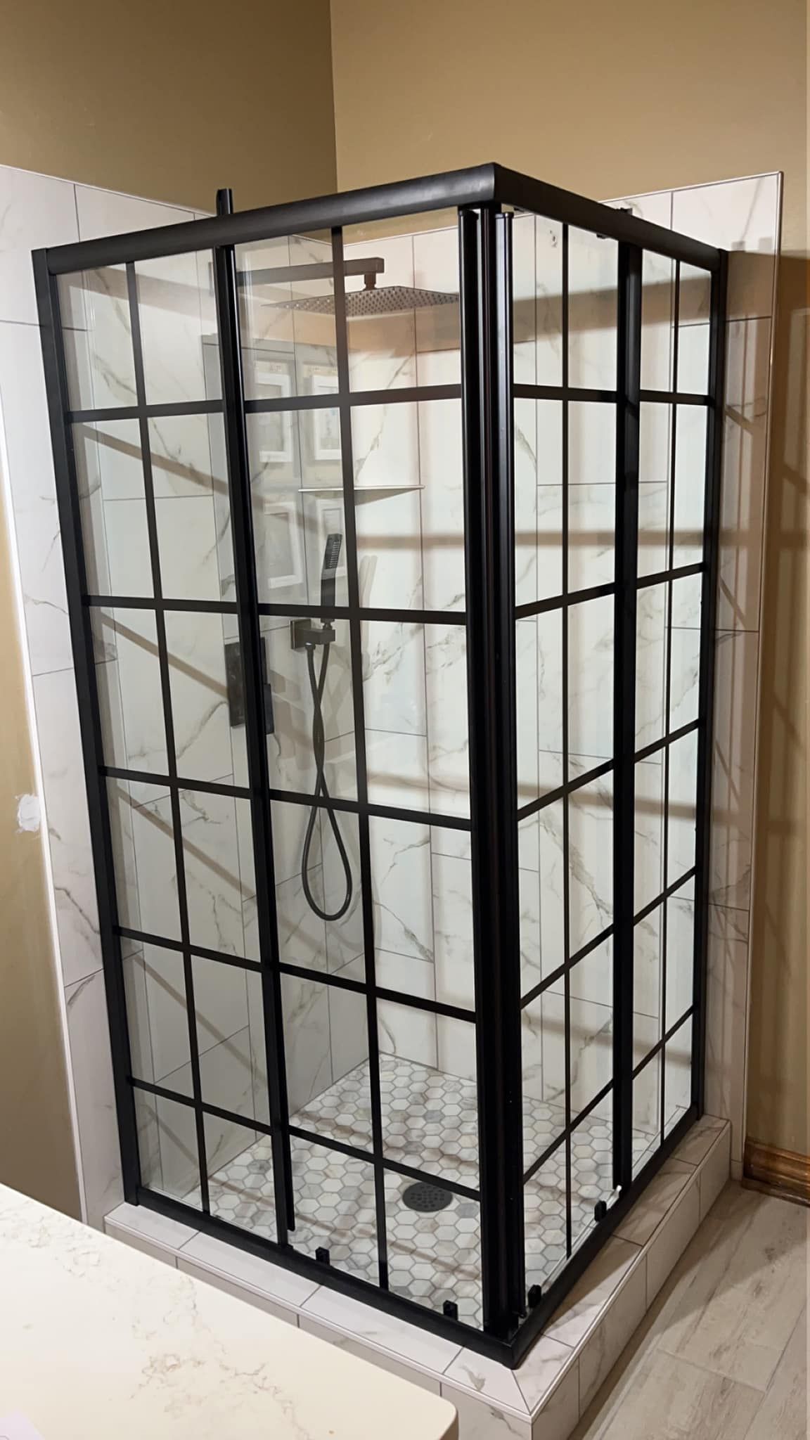 A shower stall with a black frame and glass doors in a bathroom.