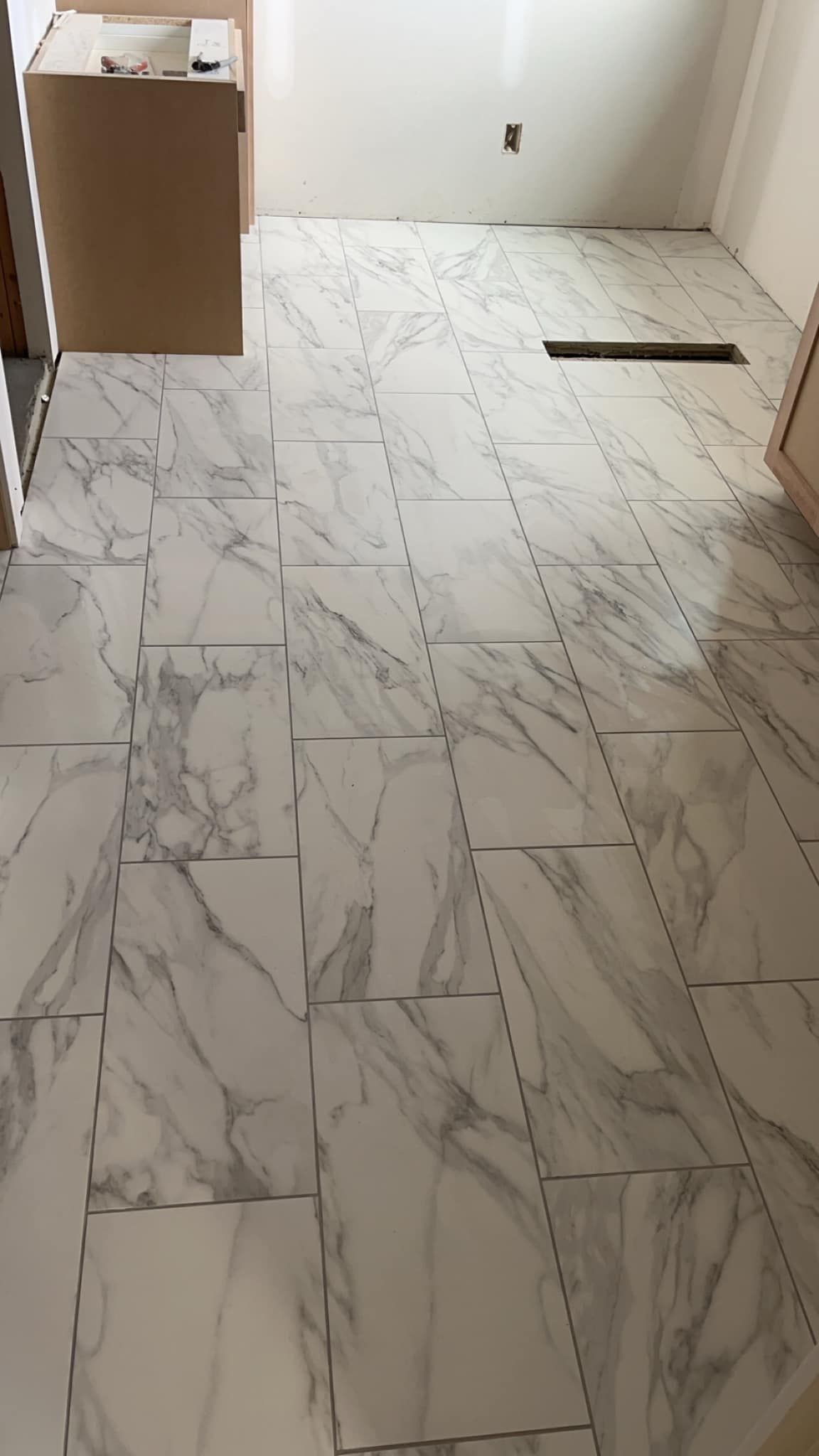 A bathroom floor with marble tiles being installed.