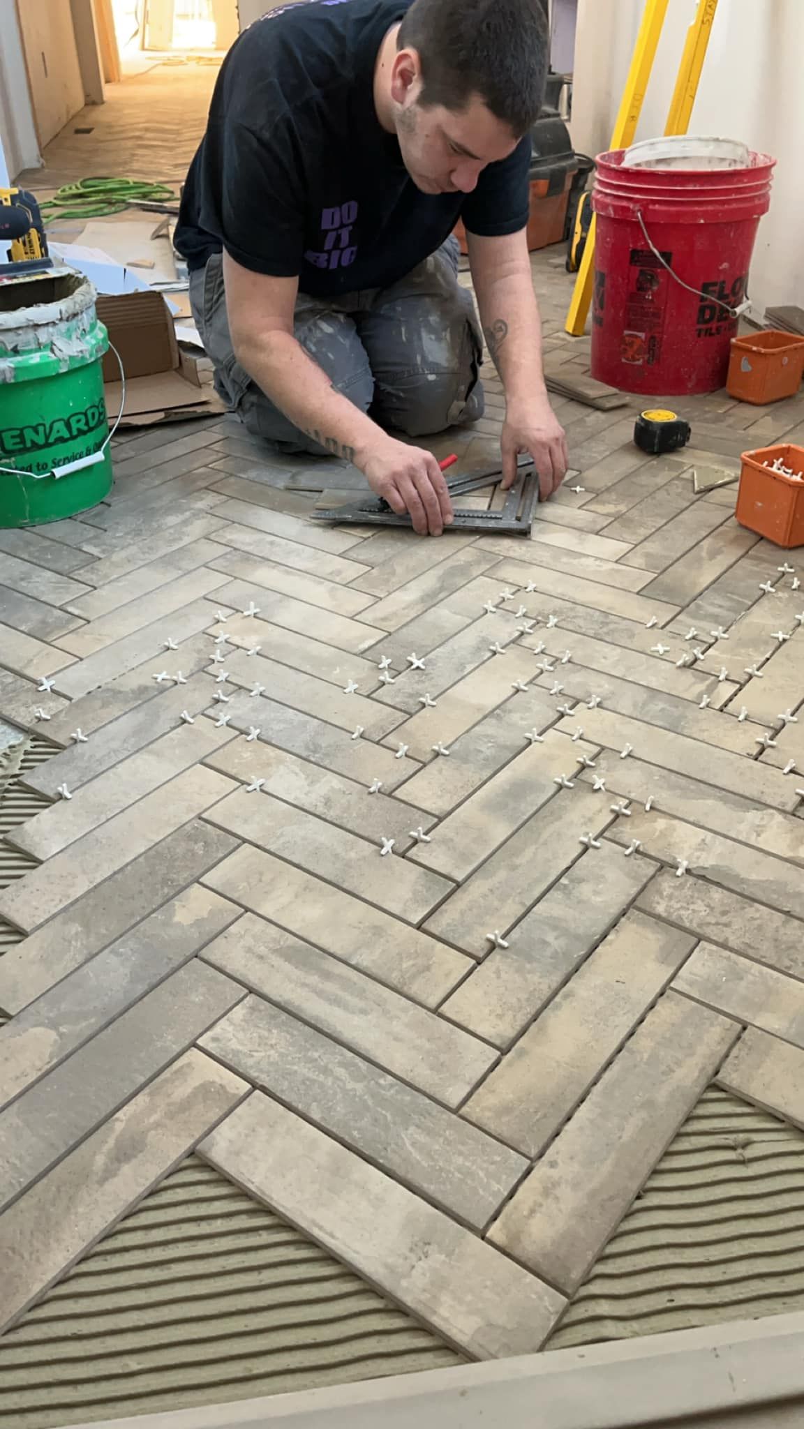 A man is laying tiles on a herringbone floor.