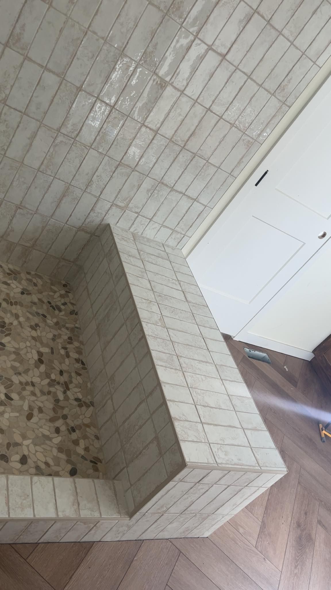 A bathroom with white tiles and a walk in shower.