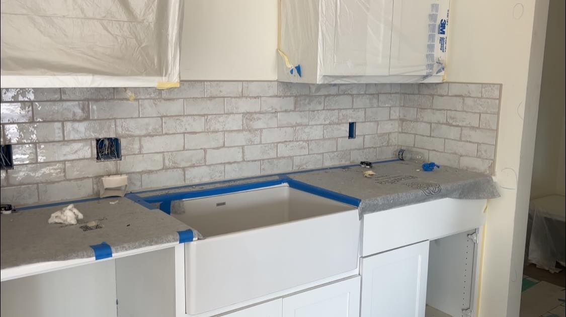 A kitchen under construction with white cabinets and a sink.