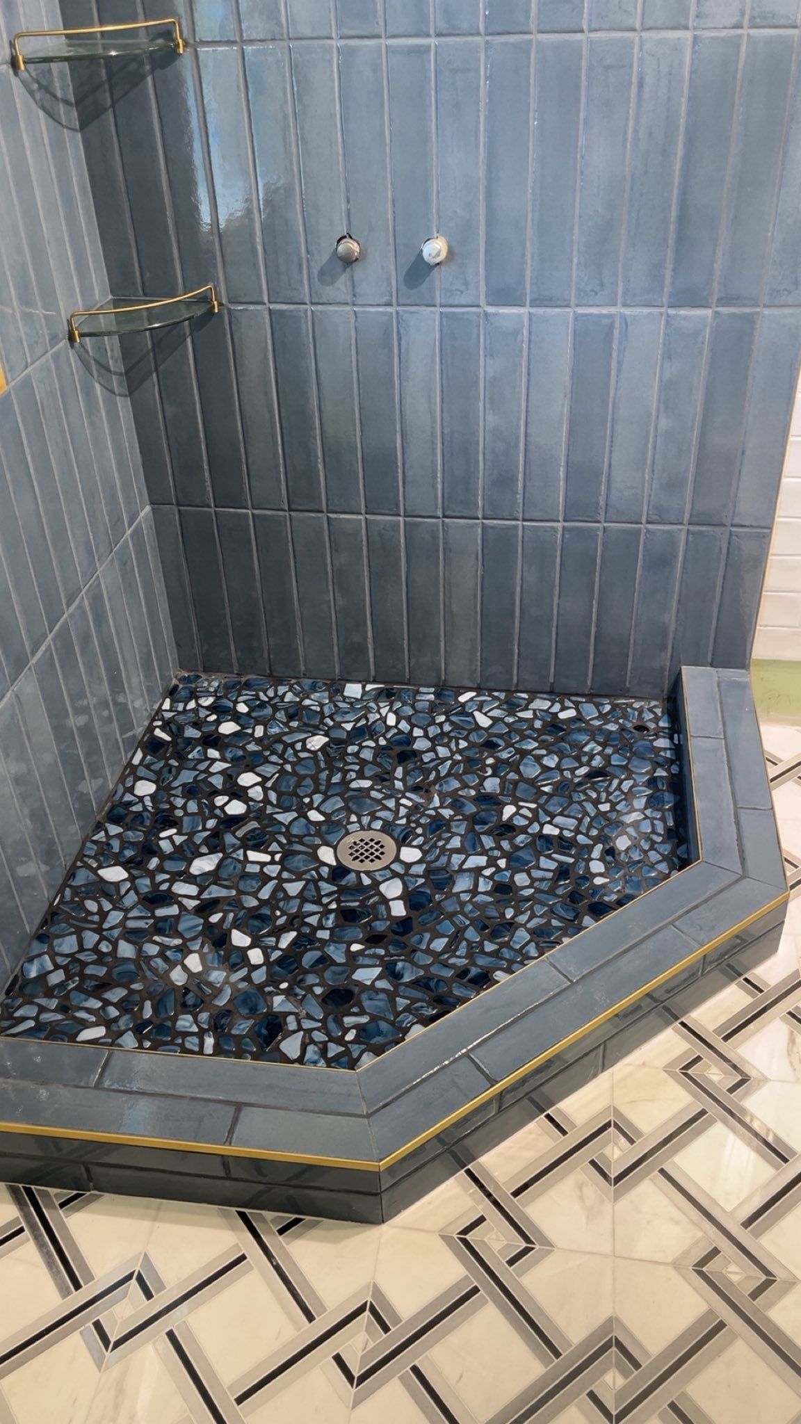 A shower stall with a tiled floor and a drain in a bathroom.