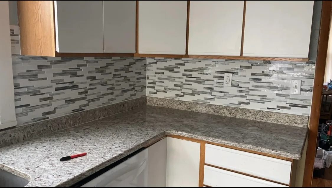 A kitchen with granite counter tops and white cabinets.