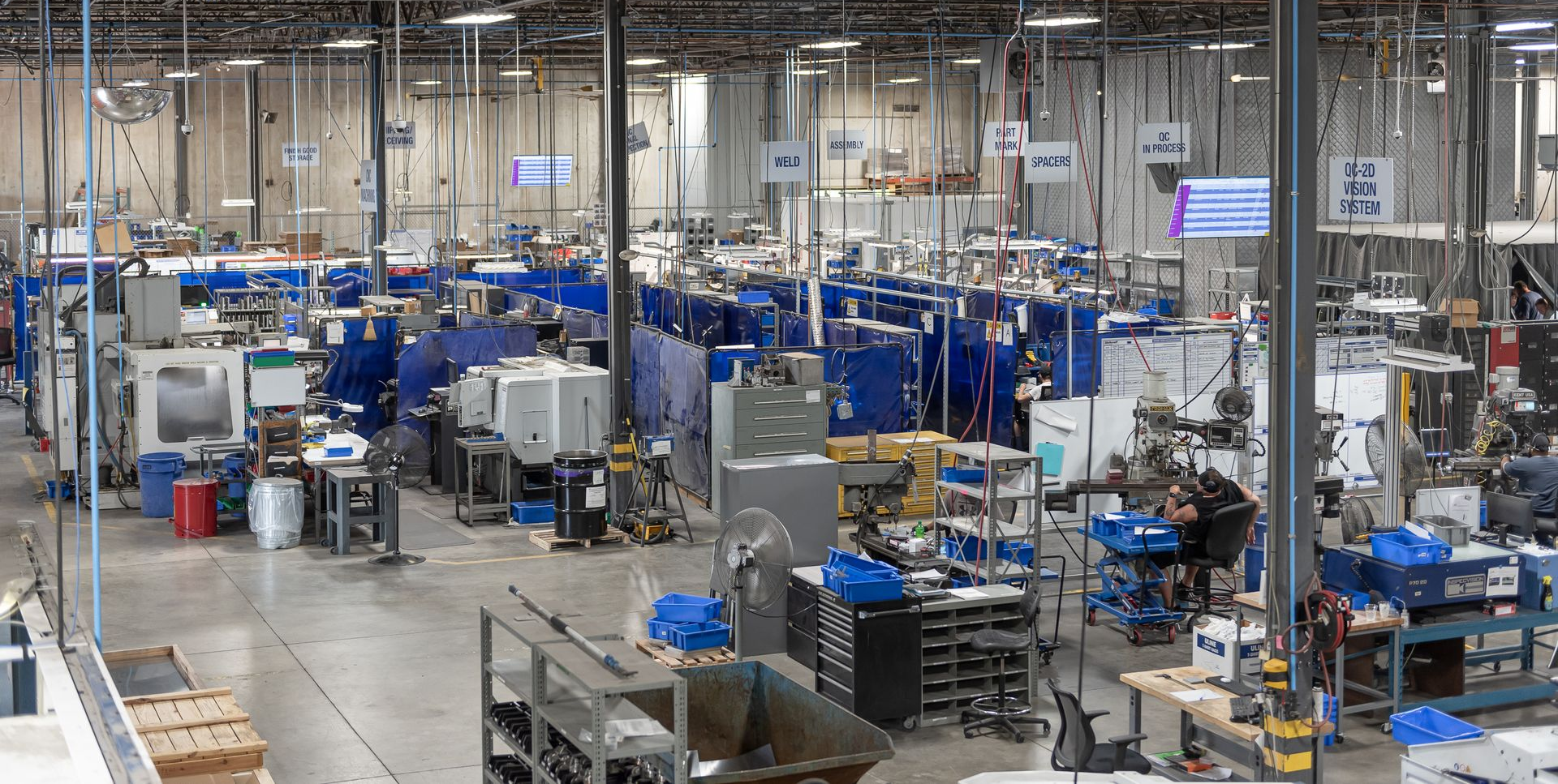 Large industrial factory floor with various machines, tools, and workers.
