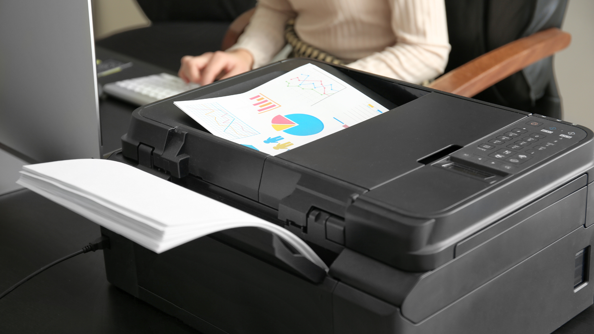 Person printing a color graph document from a black printer in an office.