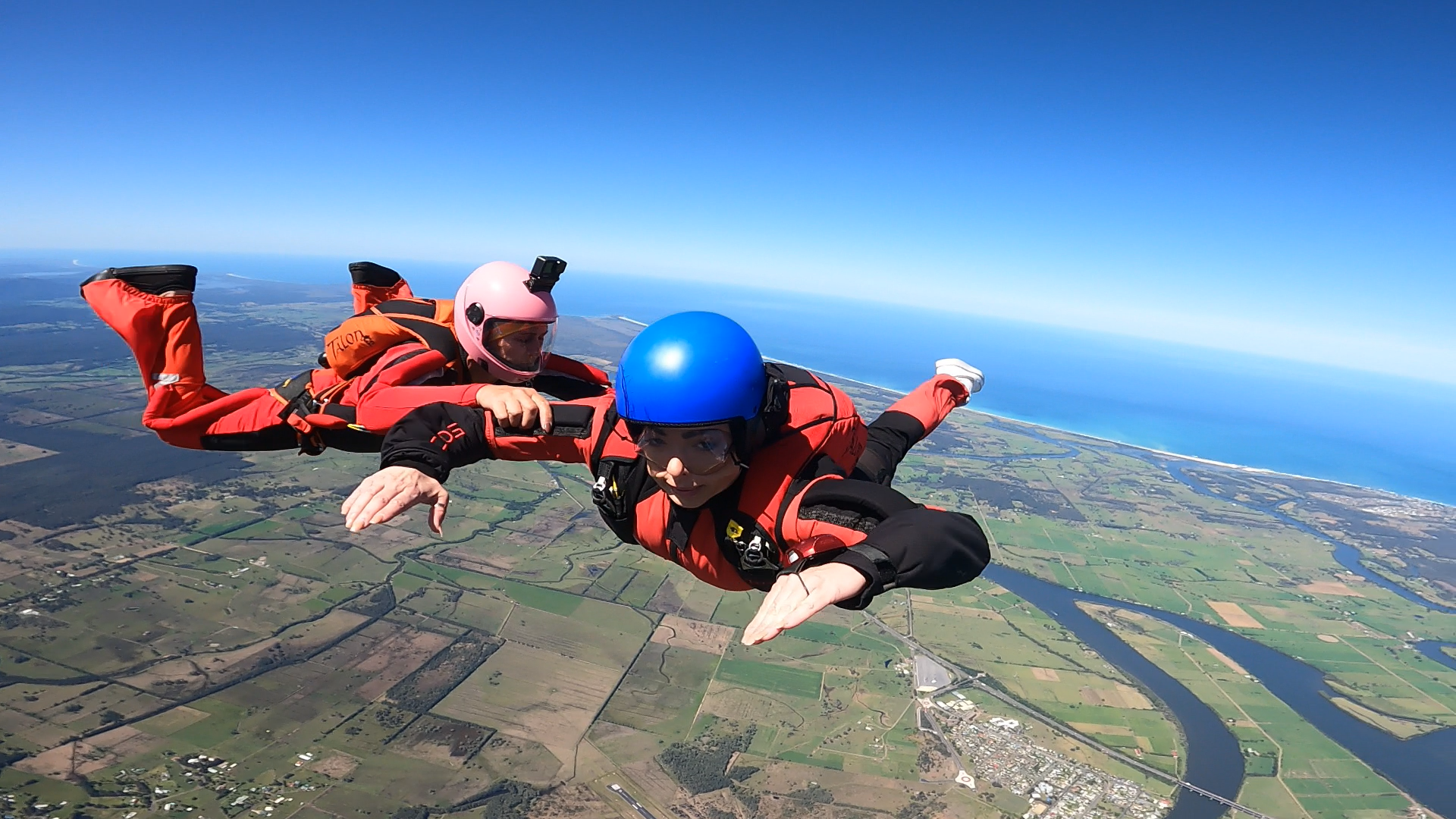 Two people are flying through the air with a river in the background.