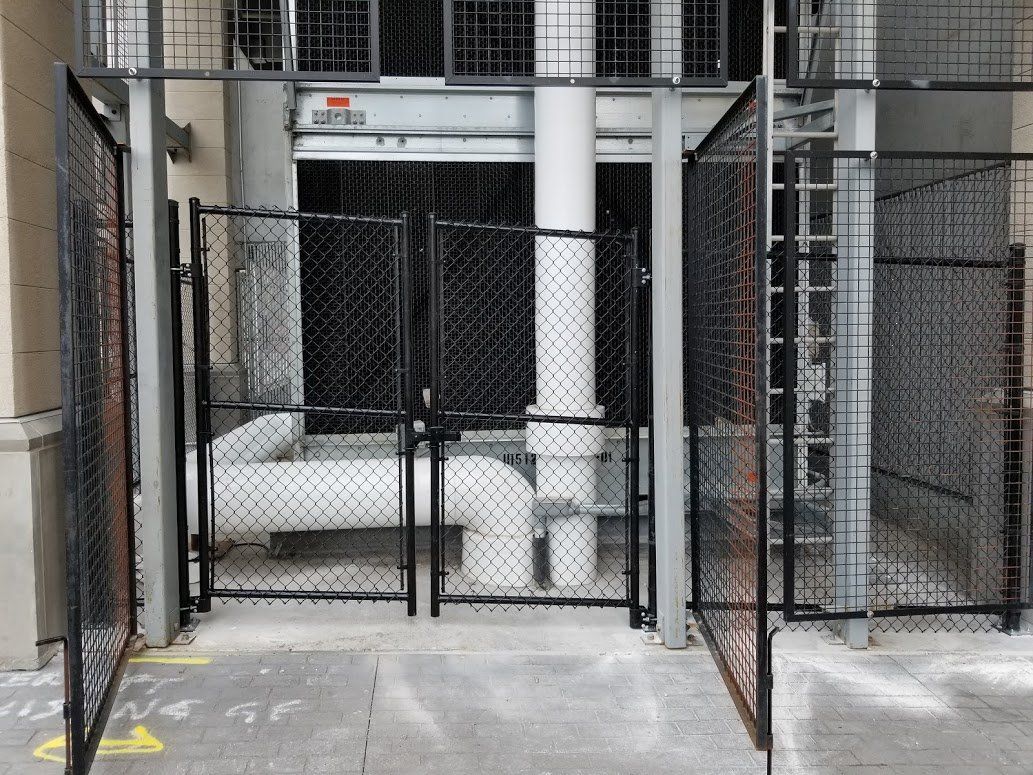 A chain link fence surrounds a building with a yellow arrow pointing to the right