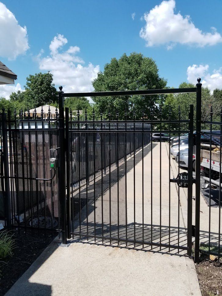 A wrought iron gate with a concrete walkway behind it