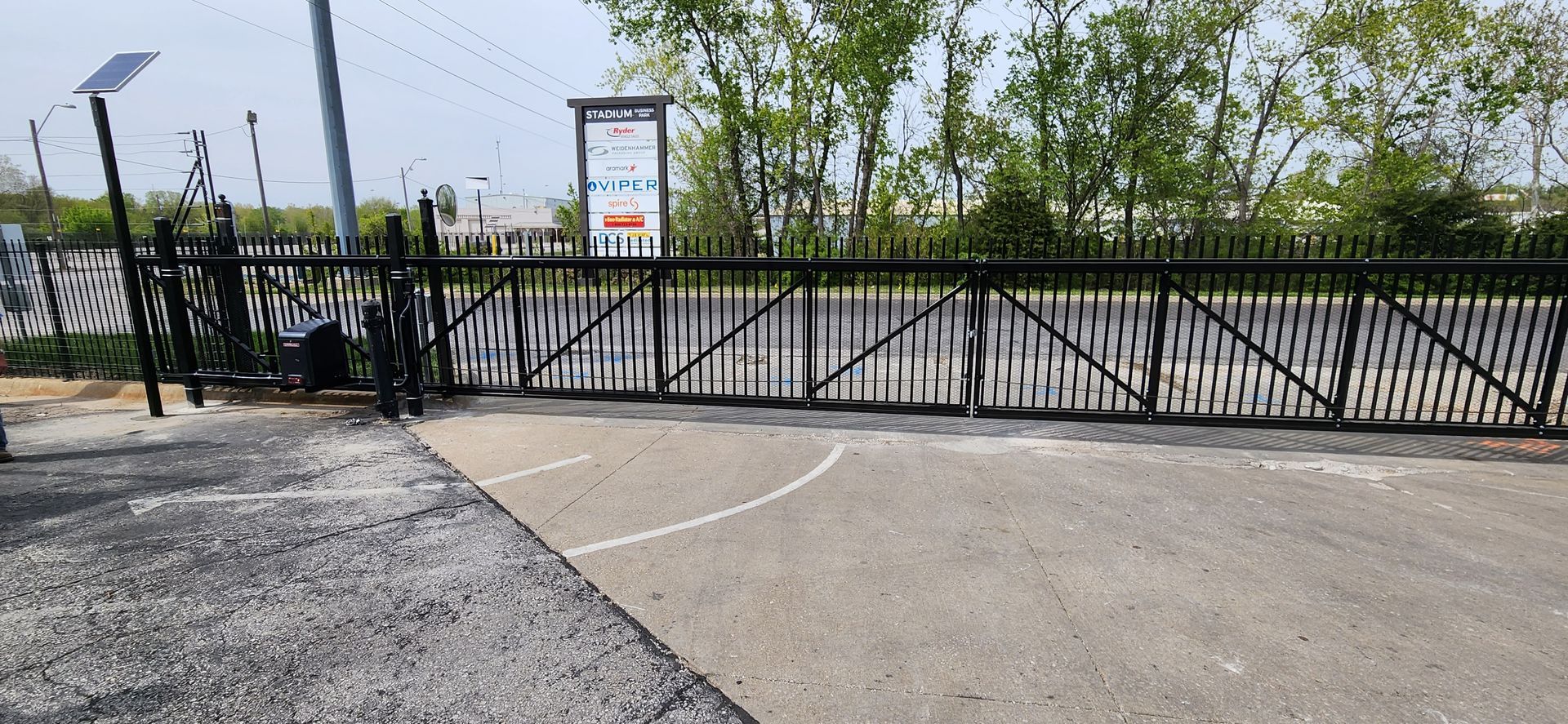 A sliding gate is open to a parking lot.