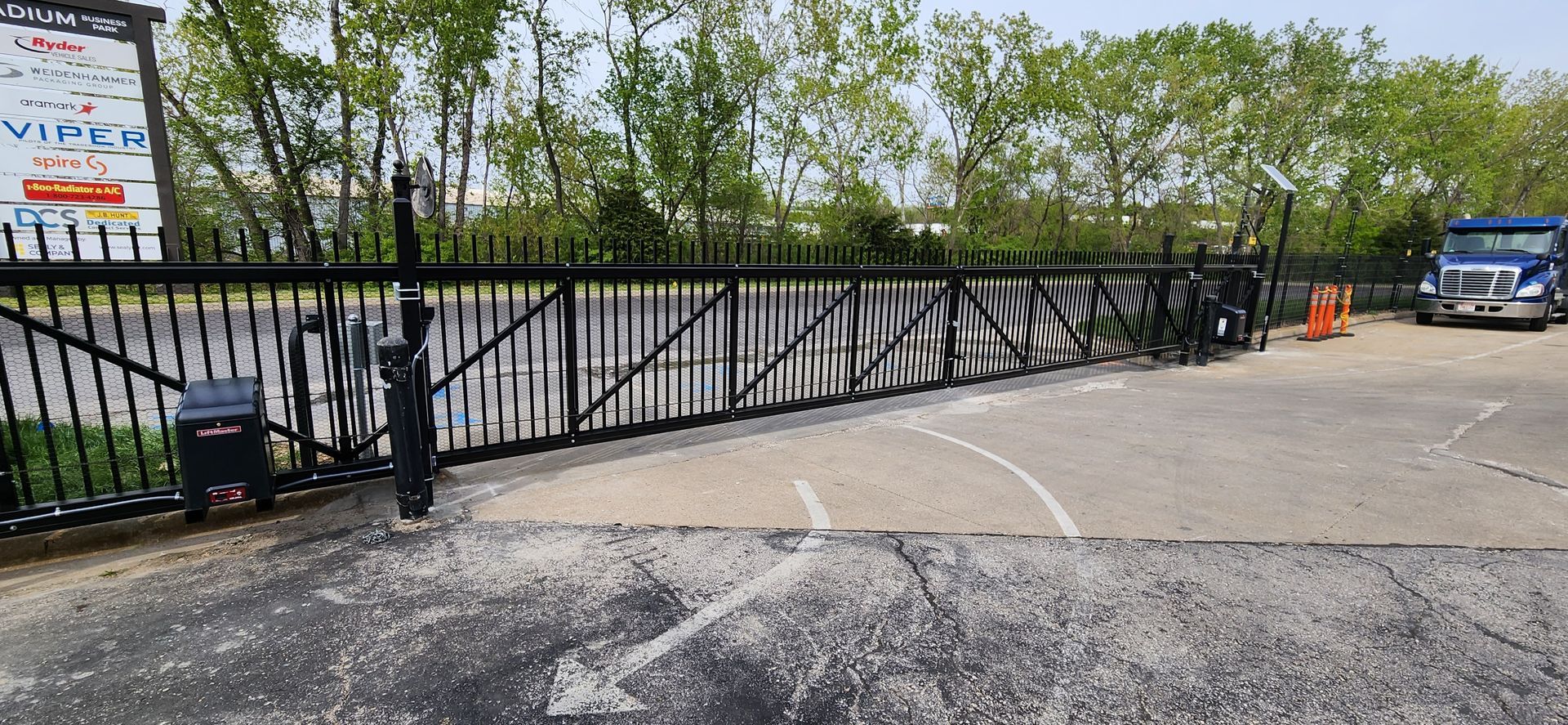 A sliding gate is open to a parking lot.