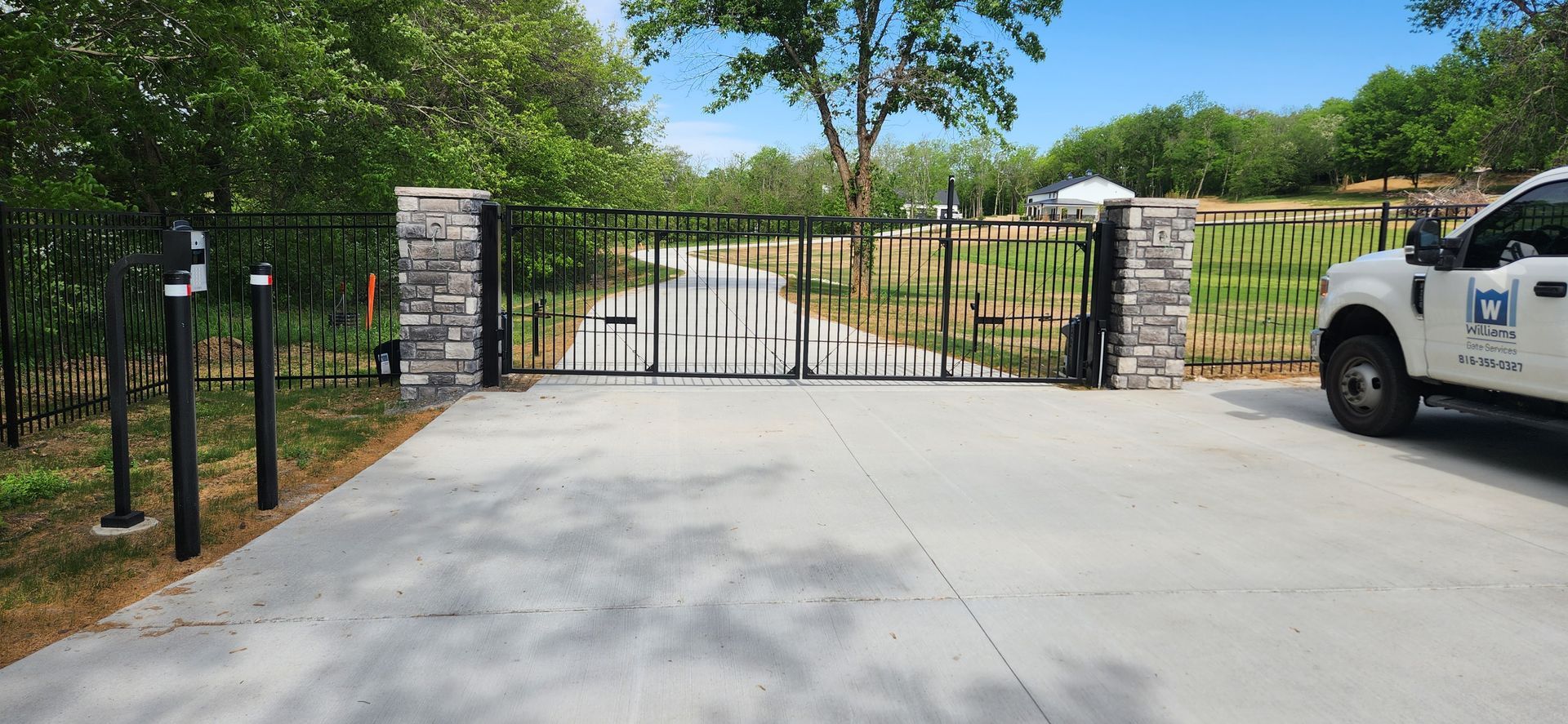 A white truck is parked in front of a gate in a driveway.