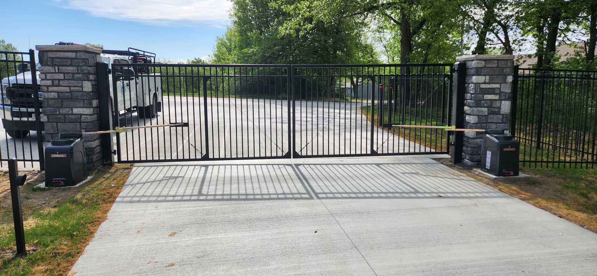 A driveway with a gate and a truck parked in front of it.
