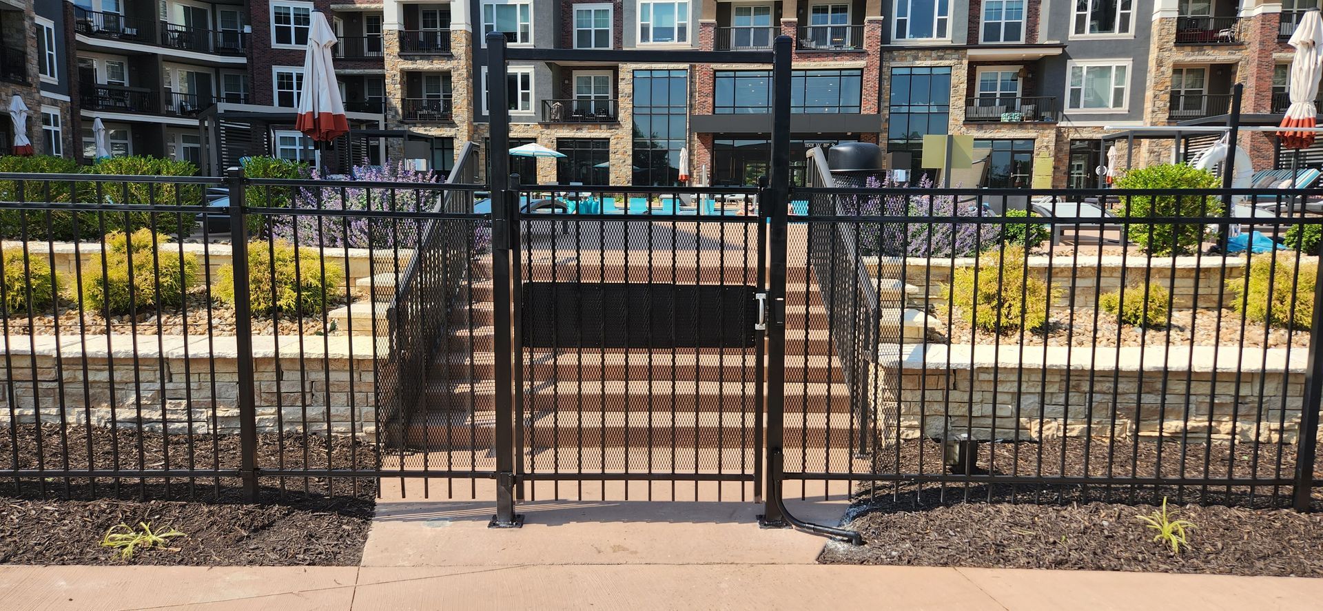 A fence with stairs leading to a pool in front of a building.